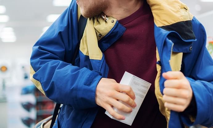 close up consumer thief’s hands putting the new gadget in the pocket in the store